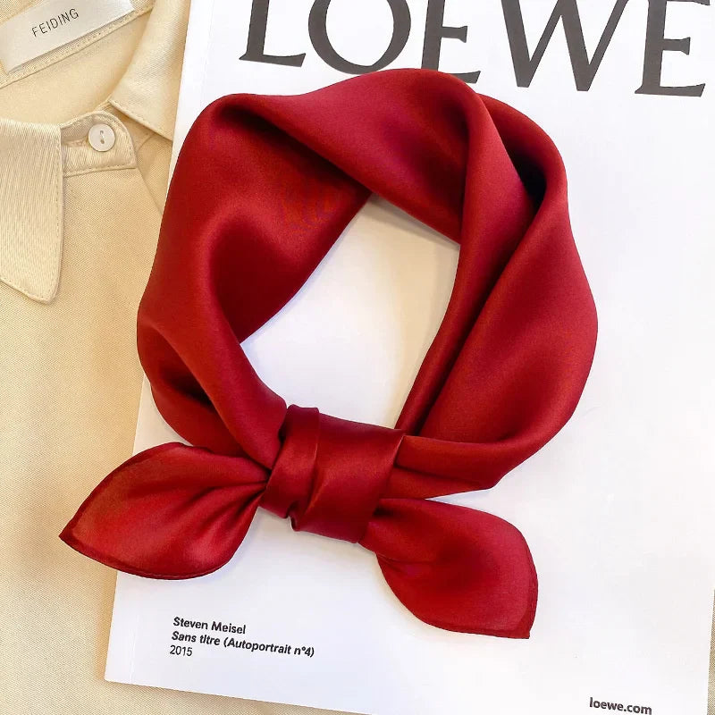 Silk Bandana Scarf - Ivory Elegant in deep red displayed on a Loewe magazine, showcasing its smooth 100% silk texture and luxurious finish.