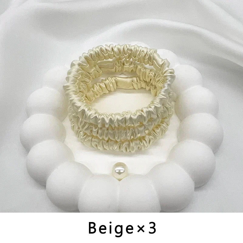 Set of three beige mulberry silk elastic hair bands. Gentle, snag-free ponytail holders for frizz-free hair styling.