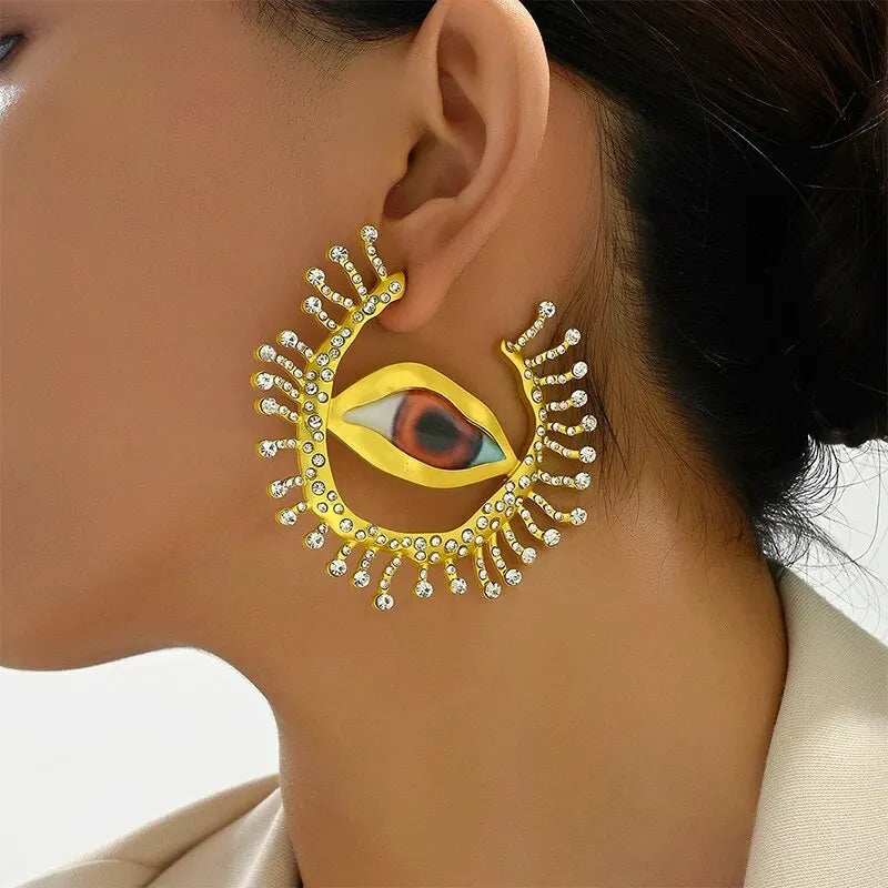 Model wearing Visionary Gaze Earrings, showcasing their bold eye-shaped design with gold-tone finish and sparkling crystals. Statement earrings for women.
