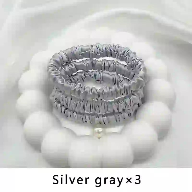 Pack of three silver gray mulberry silk elastic hair bands. Smooth, frizz-free ponytail holders for delicate or textured hair.