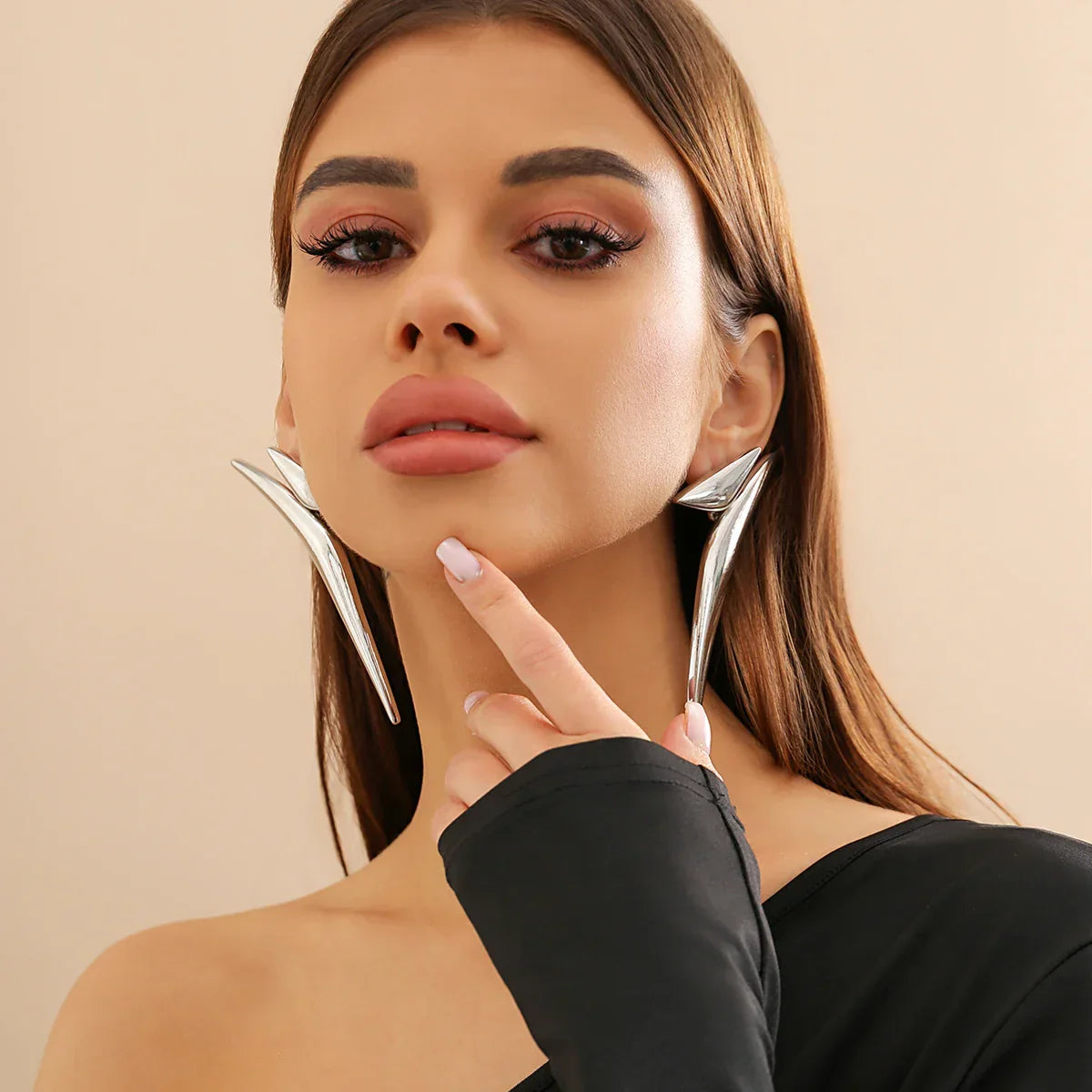 Model posing with silver-tone Sleek Aeonian Ear Wings. Bold geometric earrings for a modern and sophisticated fashion statement.
