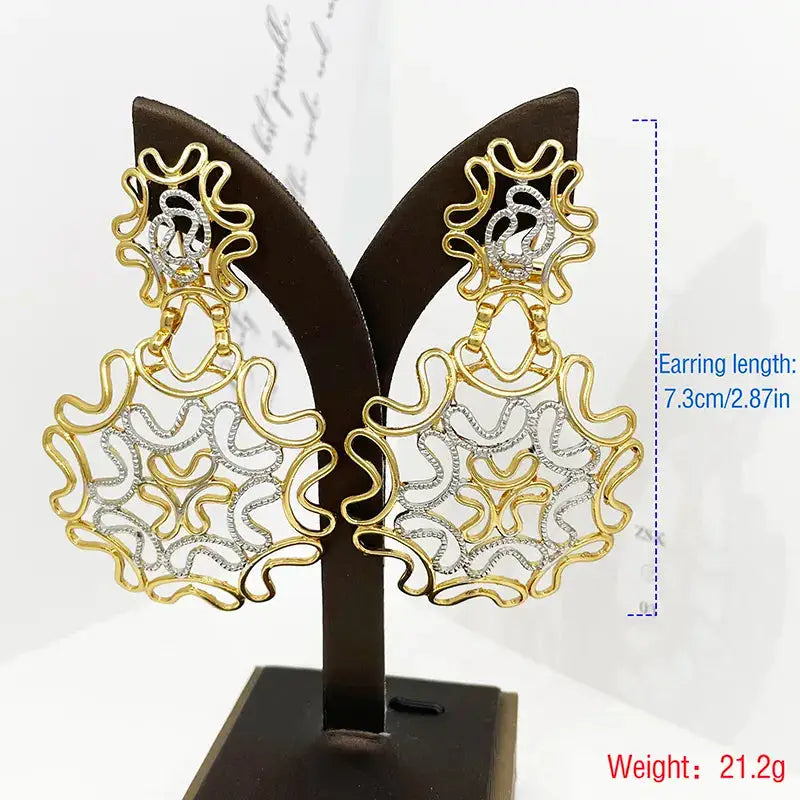 Two-tone 18k gold plated starry earrings displayed on a stand, showcasing their intricate wavy gold and silver pattern with a 7.3cm length.