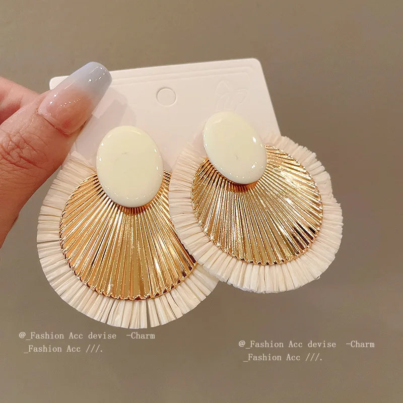 Chic ivory and gold fan tassel earrings held in hand, featuring a stylish and lightweight design ideal for modern fashion lovers.