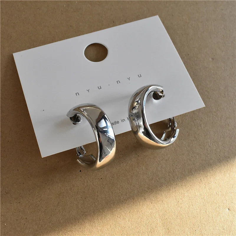 Silver-tone chunky hoop earrings displayed on a branded card. Modern vintage metal earrings for a bold fashion statement.