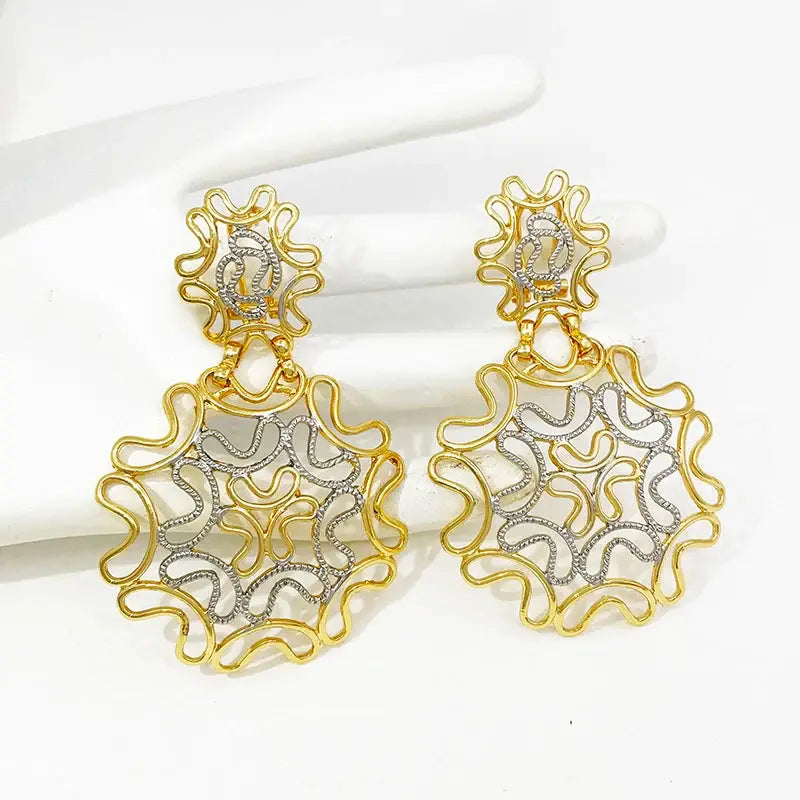 Stylish two-tone 18k gold plated starry earrings placed on a white glove, highlighting their intricate gold and silver filigree design.