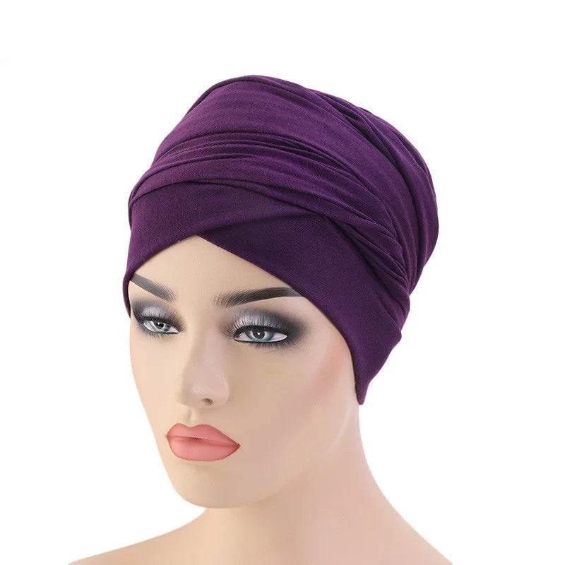 A deep purple knotted headwrap or turban cap displayed on a female mannequin head against a plain white background.