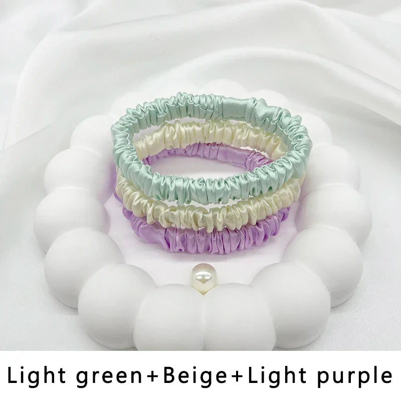 Set of three silk elastic hair bands in light green, beige, and light purple. Soft, frizz-free hold for all hair types.