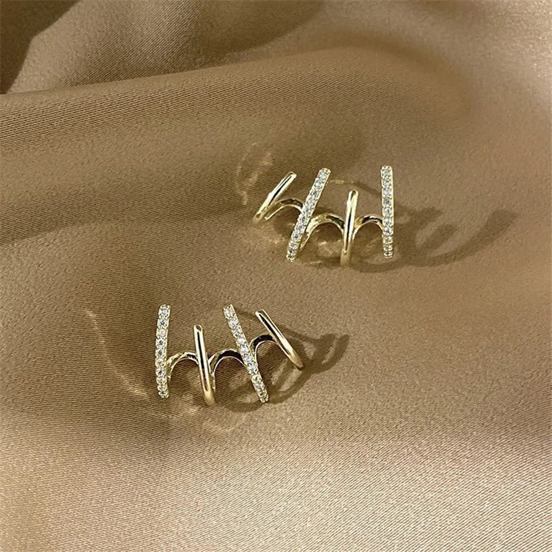 Gold-tone rhinestone ear cuffs displayed on satin fabric. Elegant and stylish modern vintage earrings for women.