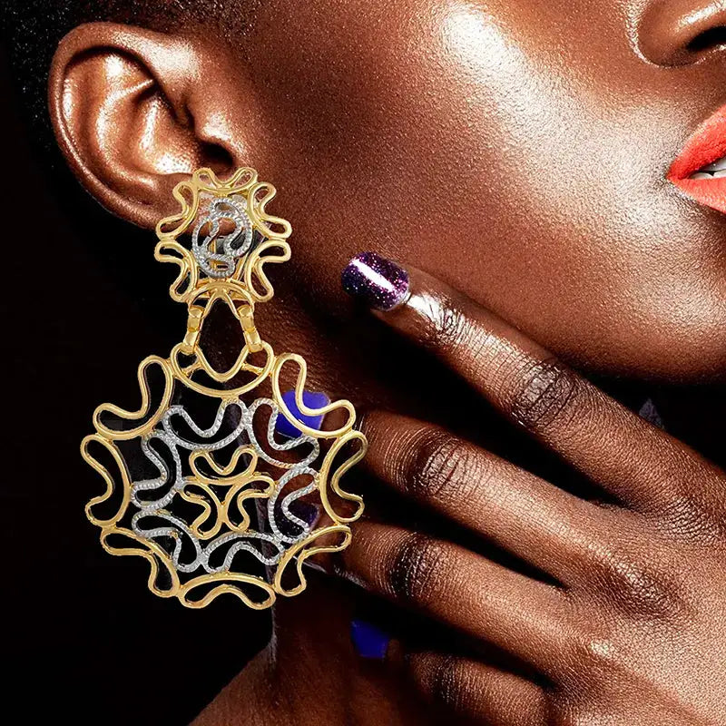 Elegant two-tone 18k gold plated starry earrings worn by a model, featuring intricate gold and silver detailing in a statement design.