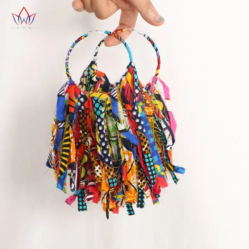 Model wearing handmade African fabric earrings with tassels. Bold, colorful design adds a statement touch to any outfit.