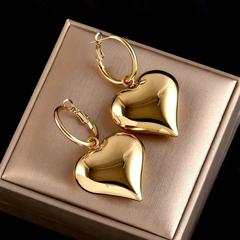 Gold Chic Heart Huggie Hoop Earrings with a polished finish, displayed on a jewelry box. Stylish and elegant accessory for any occasion.