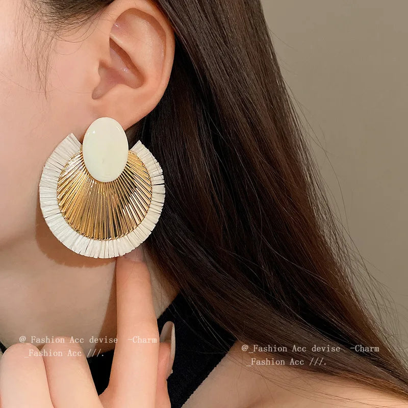 Elegant ivory and gold fan tassel earrings displayed on a model, highlighting their bold and fashionable appeal for women.