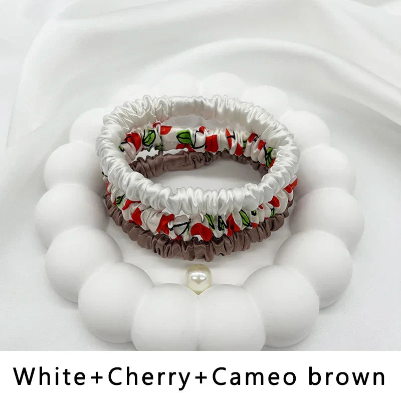 Silk hair band trio in white, cherry print, and cameo brown. Stylish, frizz-free ponytail holders for natural hair and locs.