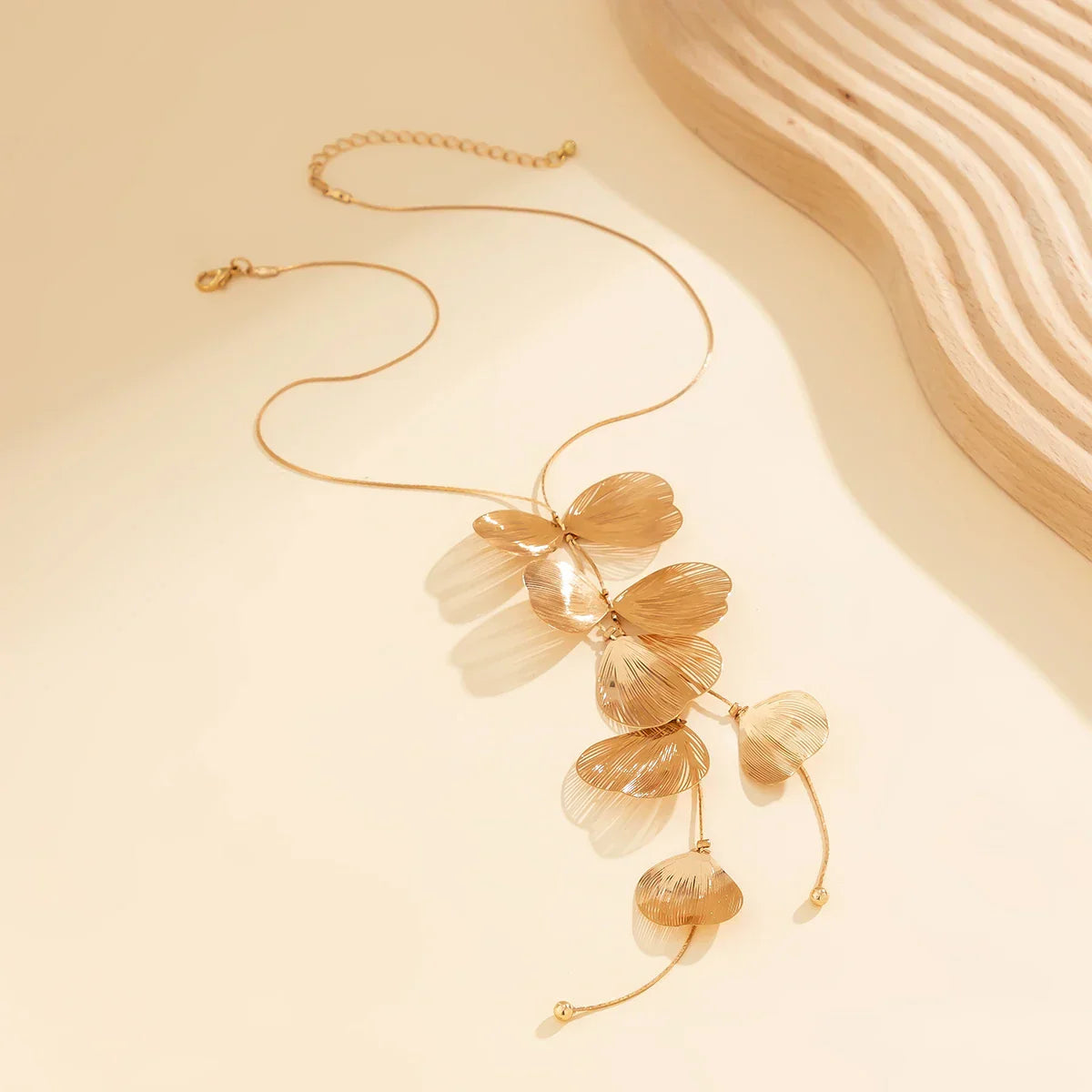 Charm Petals Long Tassel Necklace Choker displayed on a neutral background, showcasing its delicate gold-tone floral charms and elegant design.