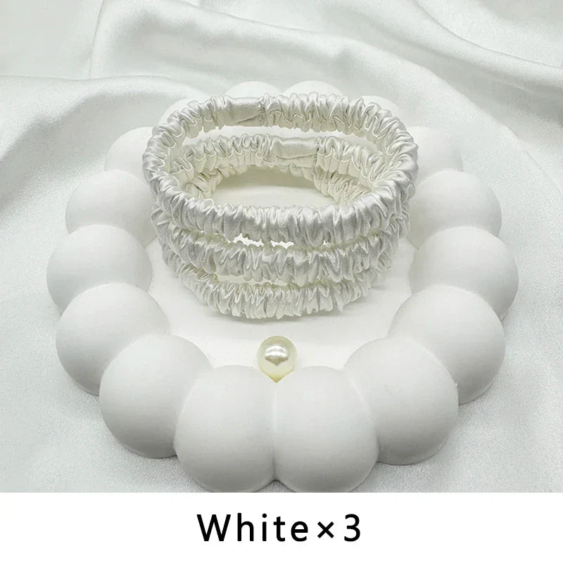 Set of three white mulberry silk elastic hair bands. Smooth, snag-free hair accessories for gentle styling and frizz control.