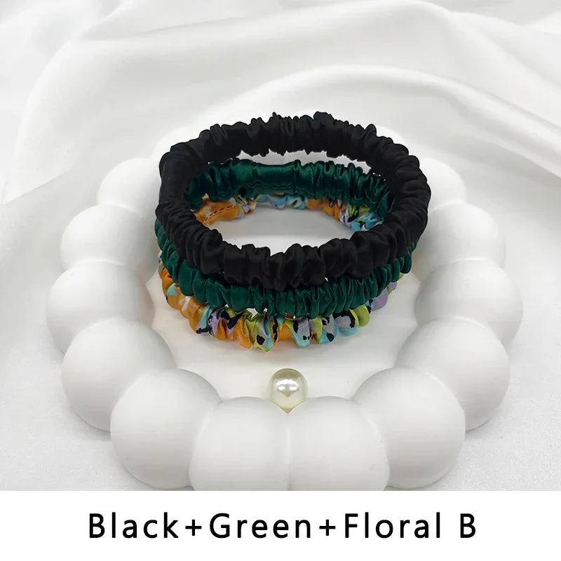 Set of three silk elastic hair bands in black, green, and floral print. Stylish, frizz-free ponytail holders for textured hair.
