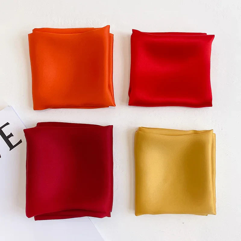 Silk Bandana Scarf - Ivory Elegant | Pure Silk, Timeless Hue in vibrant orange, red, burgundy, and gold colors, folded neatly for display.