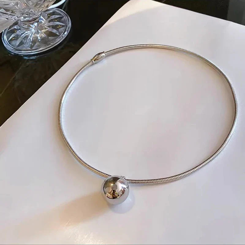 Silver choker necklace with a sleek snake chain and a polished spherical pendant, ideal for modern jewelry lovers.