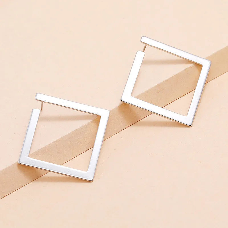 Silver-tone geometric square stud earrings displayed on a neutral background. Modern vintage earrings with a minimalist aesthetic.