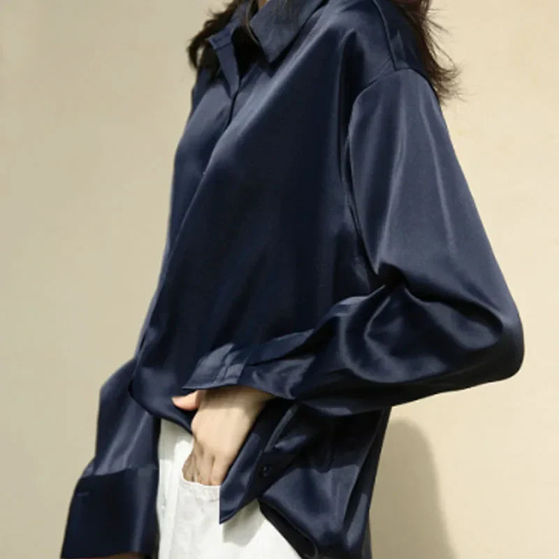 Classic champagne satin blouse styled with dark jeans for a sophisticated evening look. Features a soft, silky texture and relaxed fit.