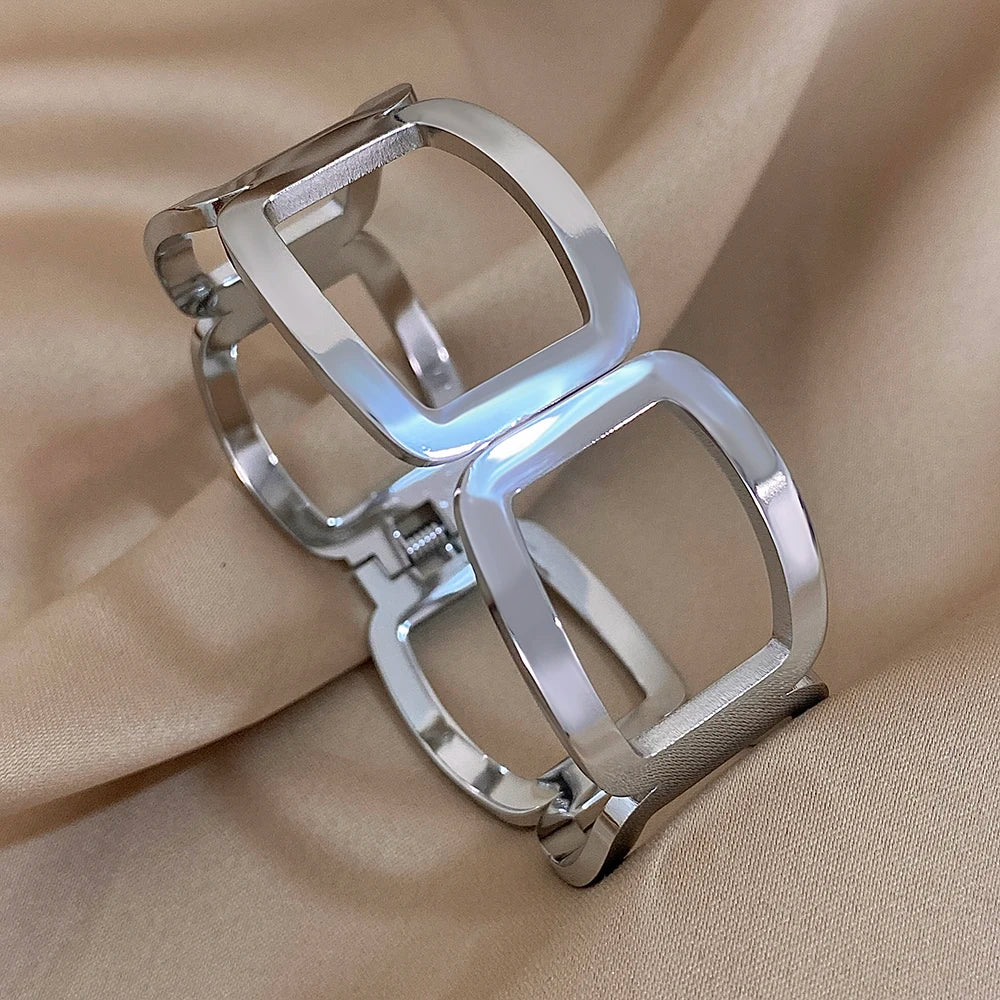 Silver open-frame link cuff with a hinge and spring closure, on beige satin