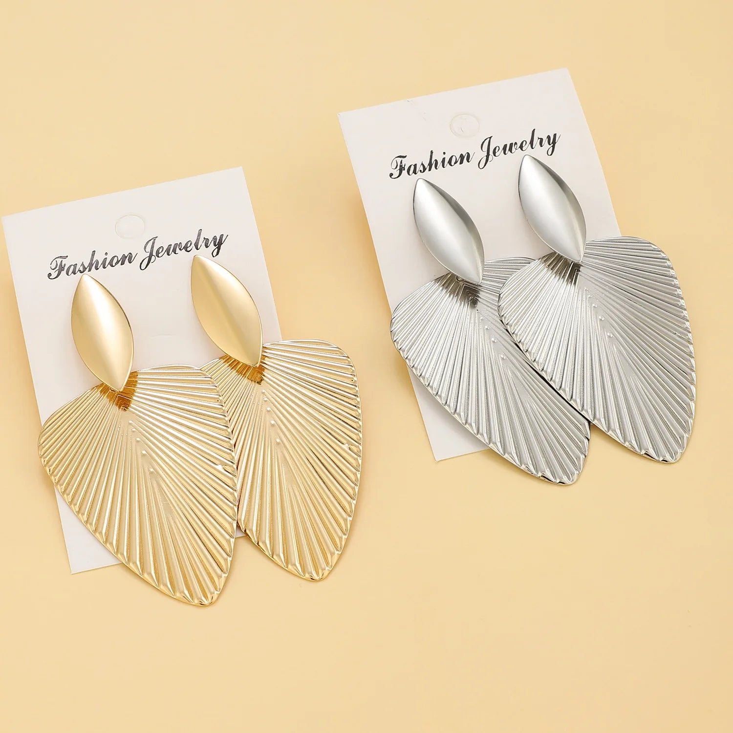 Gold and silver fan statement earrings on fashion jewelry cards, showcasing their sleek and textured design. Ideal for vintage and modern fashion lovers.