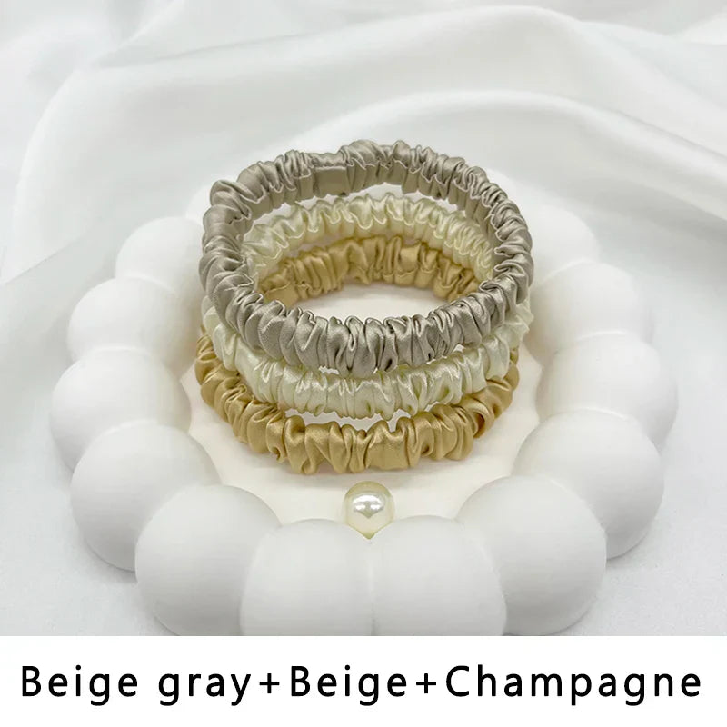 Three-piece set of silk elastic hair bands in beige gray, beige, and champagne. Gentle, frizz-free hold for natural hair.