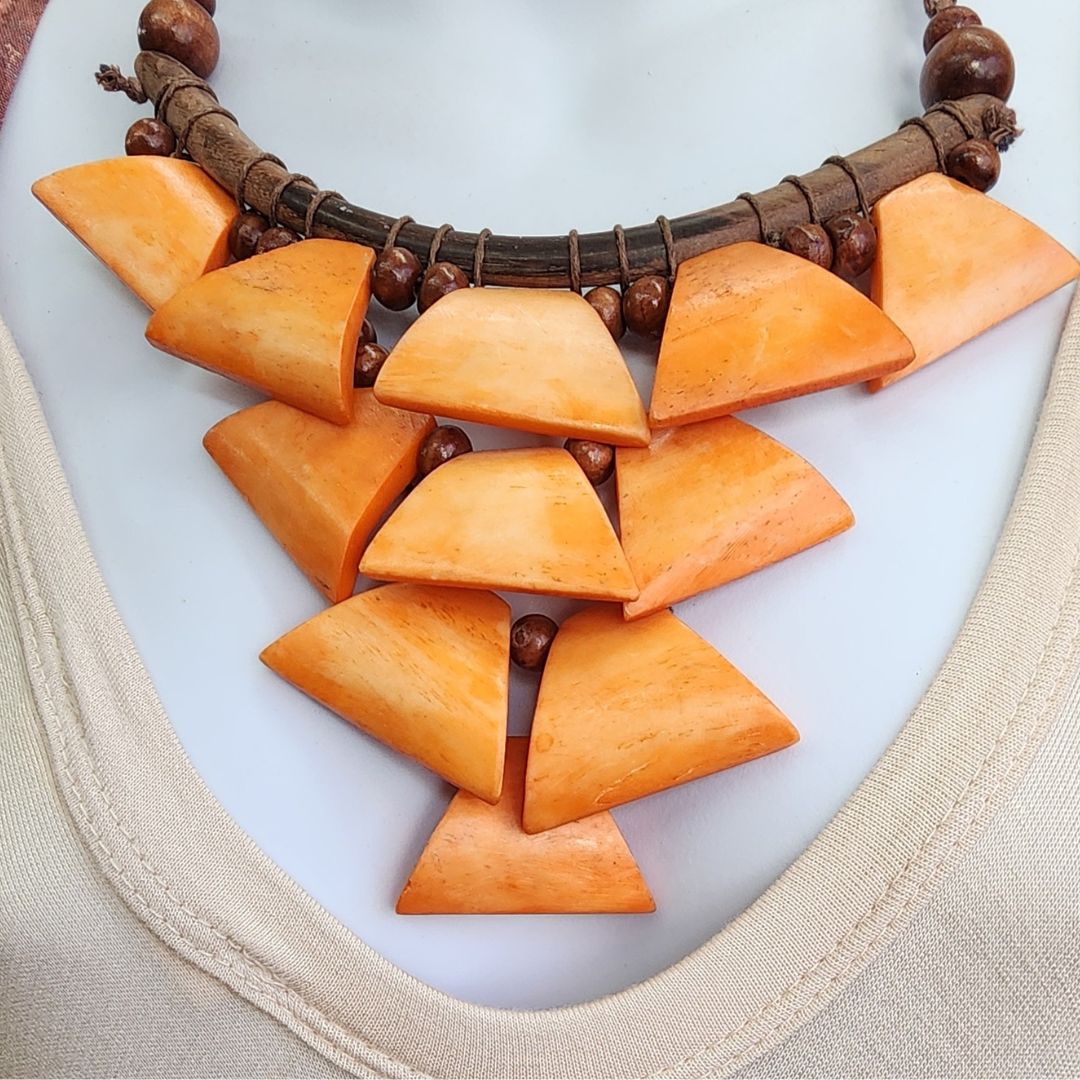 Savanna Sunburst Wooden Necklace featuring handcrafted wooden beads and vibrant orange geometric pendants. A bold statement piece for any outfit.