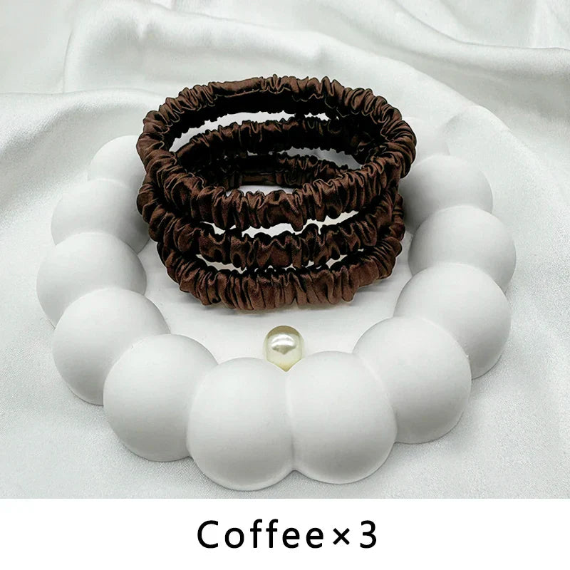 Set of three coffee-colored mulberry silk elastic hair bands. Smooth, snag-free hold for frizz-free styling.