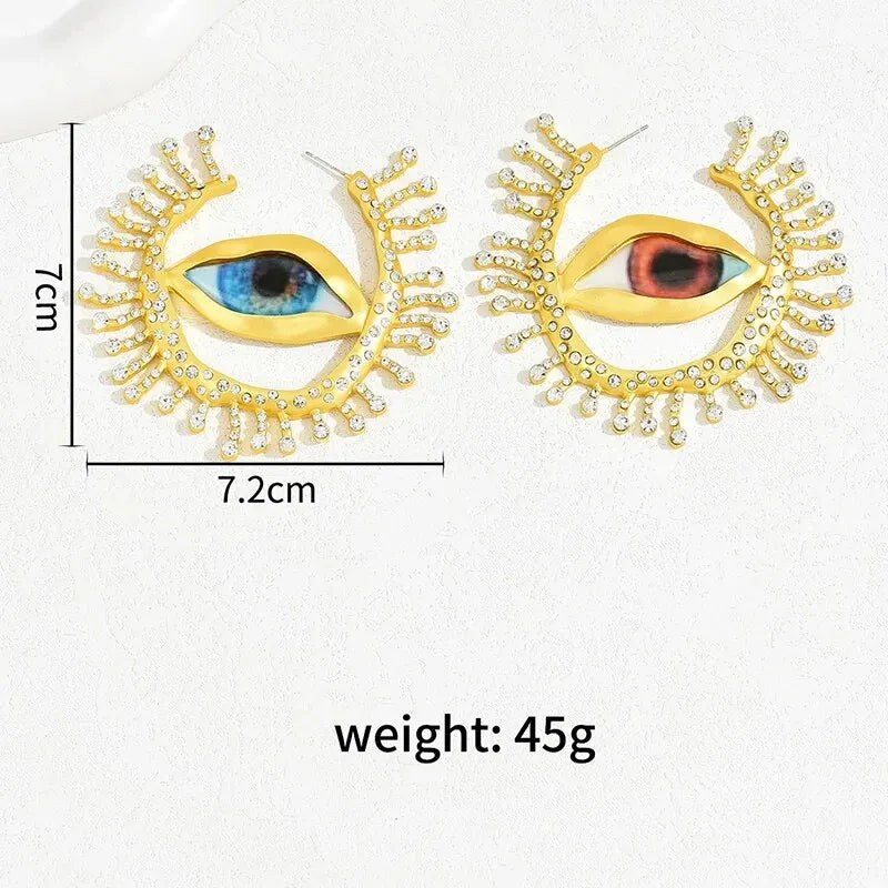 Visionary Gaze Earrings with size and weight details, featuring a gold-tone eye design with crystal accents. Bold and artistic fashion earrings.