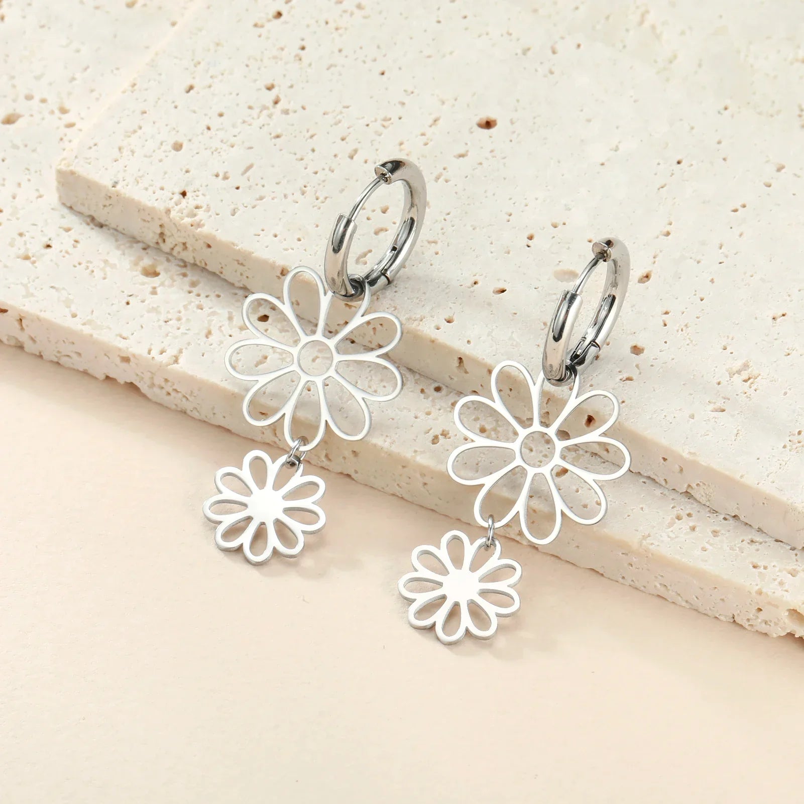 Silver flower drop earrings with a double floral charm and hoop closure. Elegant and lightweight accessory for a chic and modern look.