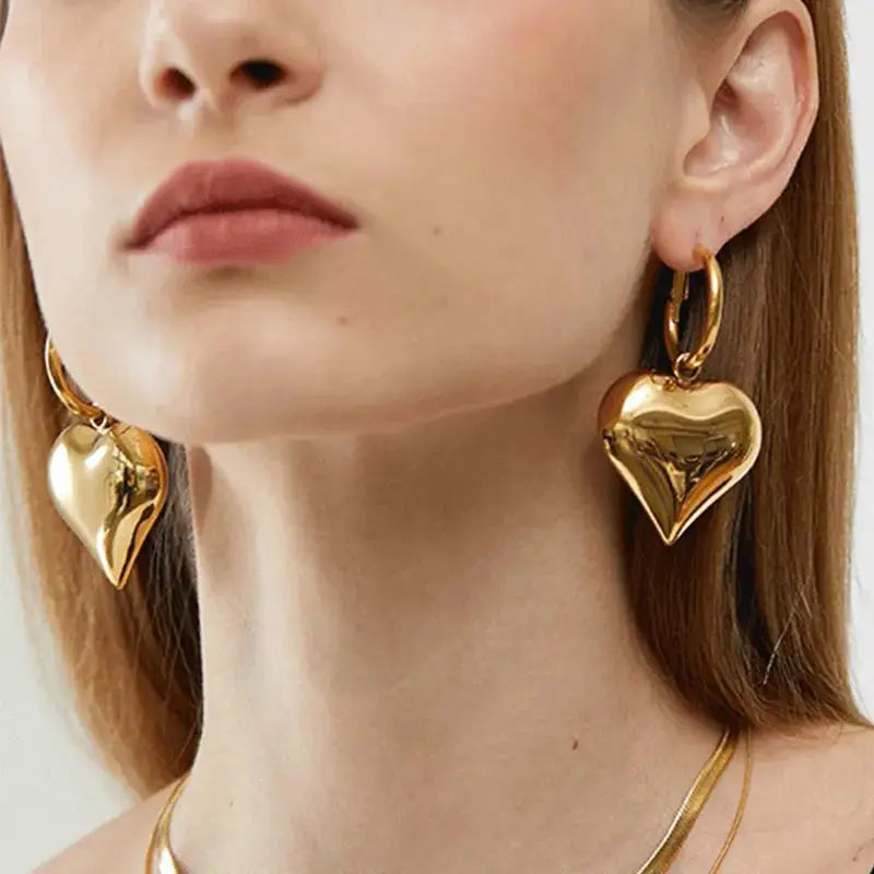 Model wearing gold Chic Heart Huggie Hoop Earrings, showcasing their bold and elegant design. Ideal for stylish outfits.