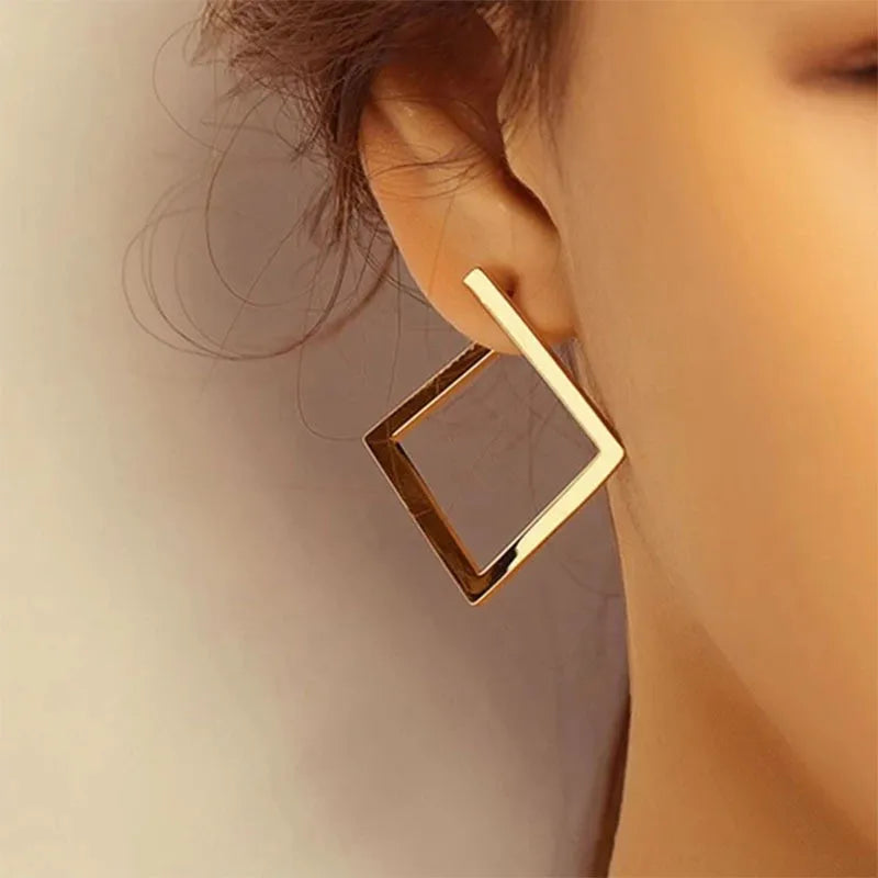 Gold-tone geometric square stud earrings worn by a model, featuring a modern vintage design. Elegant and stylish earrings for women.