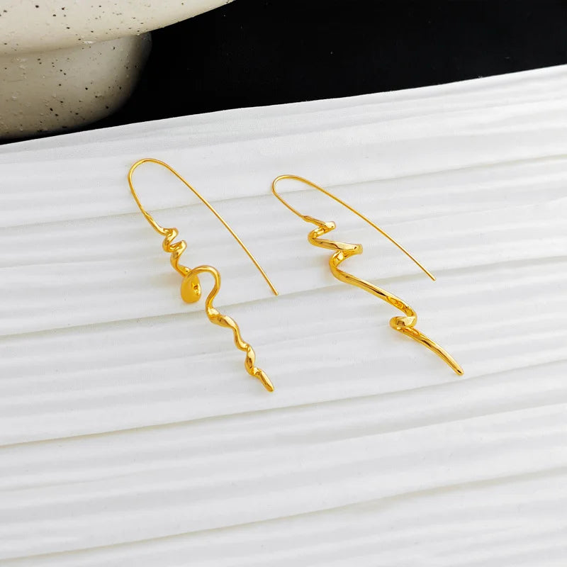 Gold earrings on a white surface with a black background