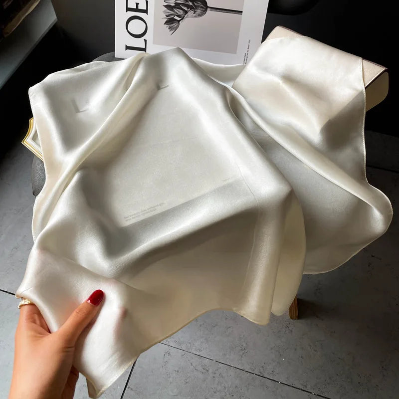 Silk Bandana Scarf - Ivory Elegant draped over a chair, showcasing its smooth 100% silk texture and subtle sheen. A timeless clothing accessory for refined style.