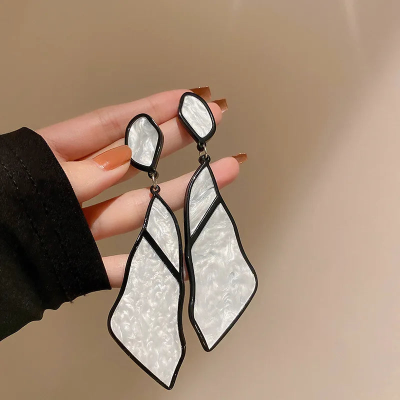 Red Oceanic Shard Drop Earrings held in hand. Bold geometric earrings with a marbled finish, ideal for making a fashion statement.