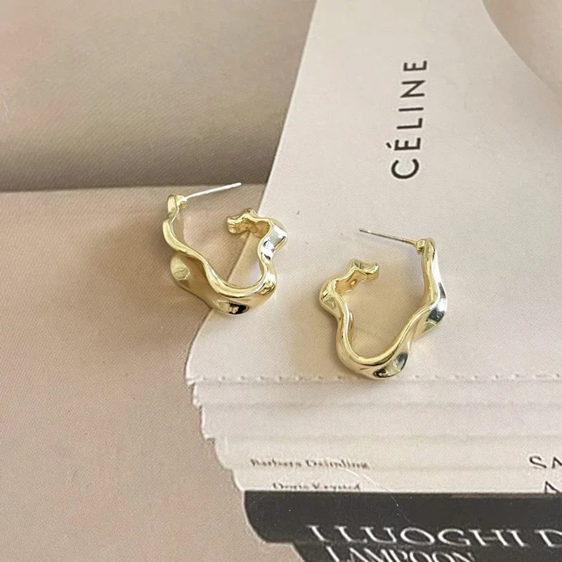 Gold-tone irregular hoop earrings displayed on a neutral background. Elegant and trendy modern vintage earrings for women.