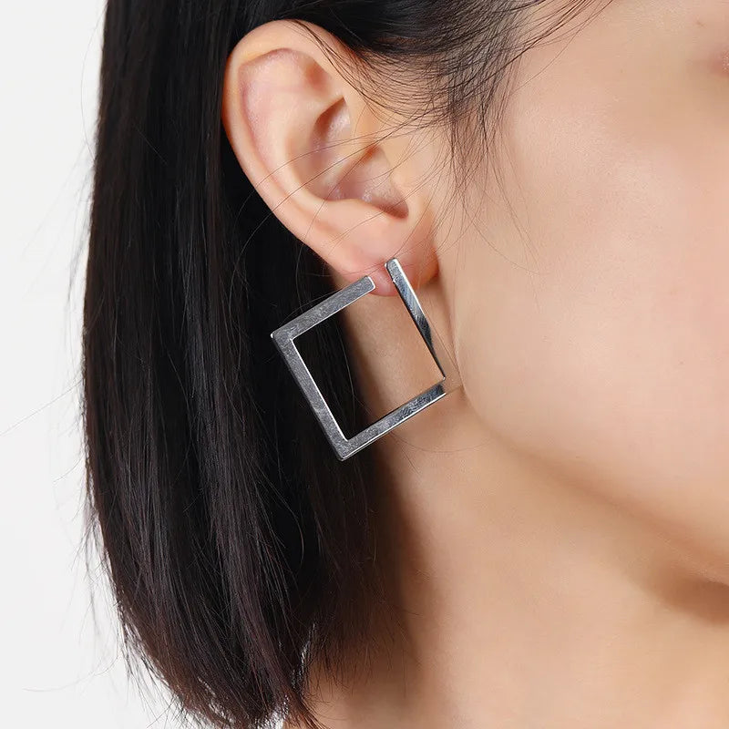 Silver geometric square stud earrings worn by a model, showcasing a modern vintage design. Elegant and trendy earrings for women.