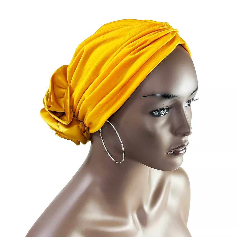 Yellow floral stretch bandana head wrap styled on a mannequin. Bright and elegant design with a fabric rose detail at the back.