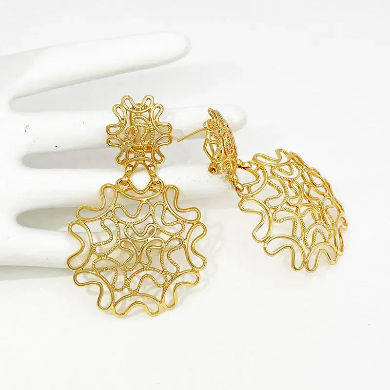 Two-tone 18k gold plated starry earrings placed on a white glove, showcasing their delicate gold and silver filigree with a lightweight design.