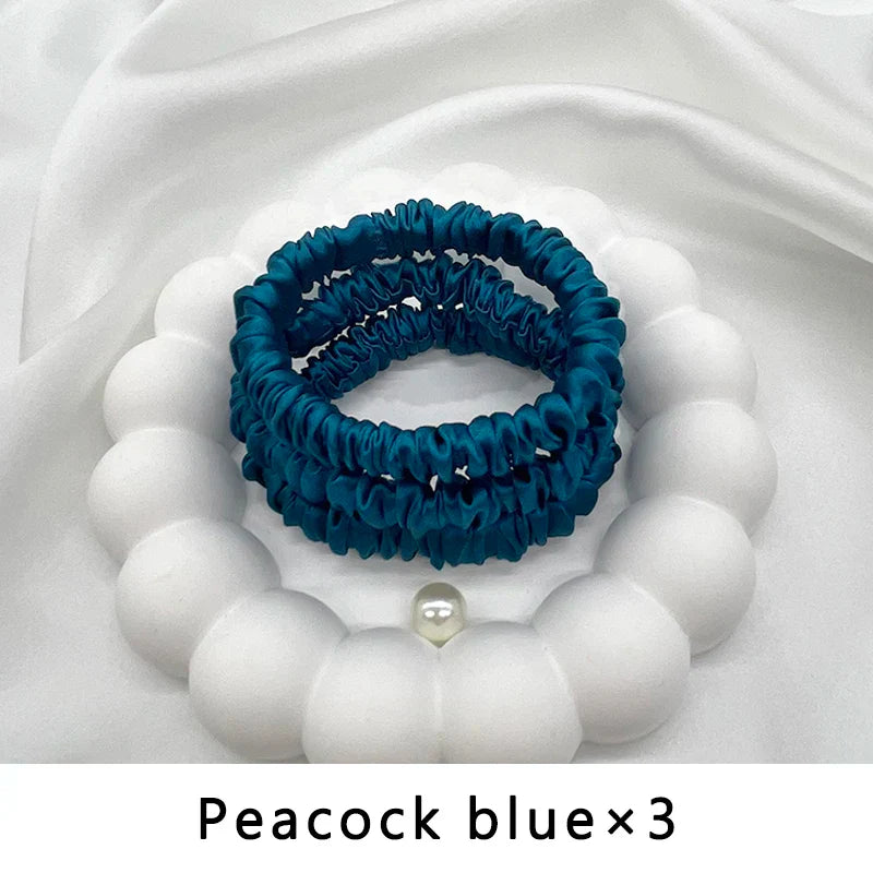 Set of three peacock blue mulberry silk elastic hair bands. Frizz-free, snag-free hold for natural hair and locs.