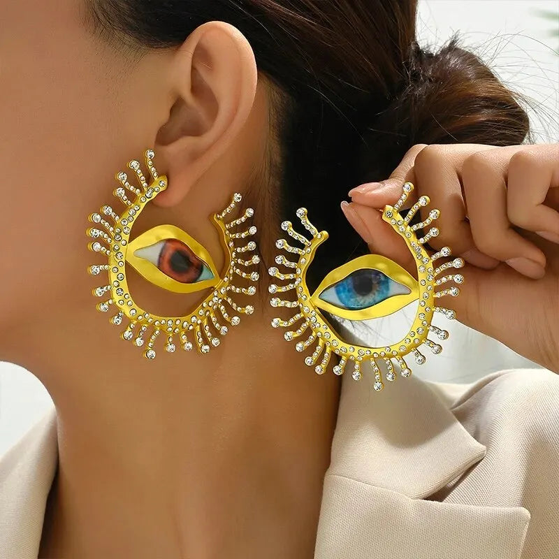 Close-up of Visionary Gaze Earrings worn by a model, highlighting the striking eye motif and shimmering crystal accents. Trendy fashion earrings.