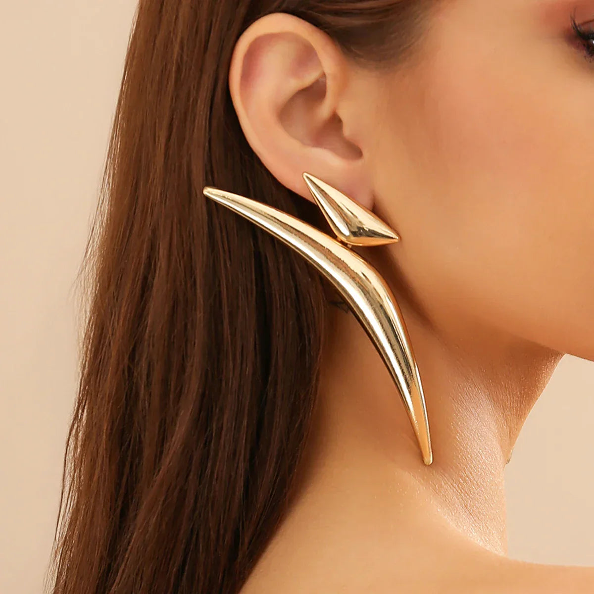 Model wearing Sleek Aeonian Ear Wings, showcasing their striking geometric shape. Elegant gold-tone earrings for a contemporary look.