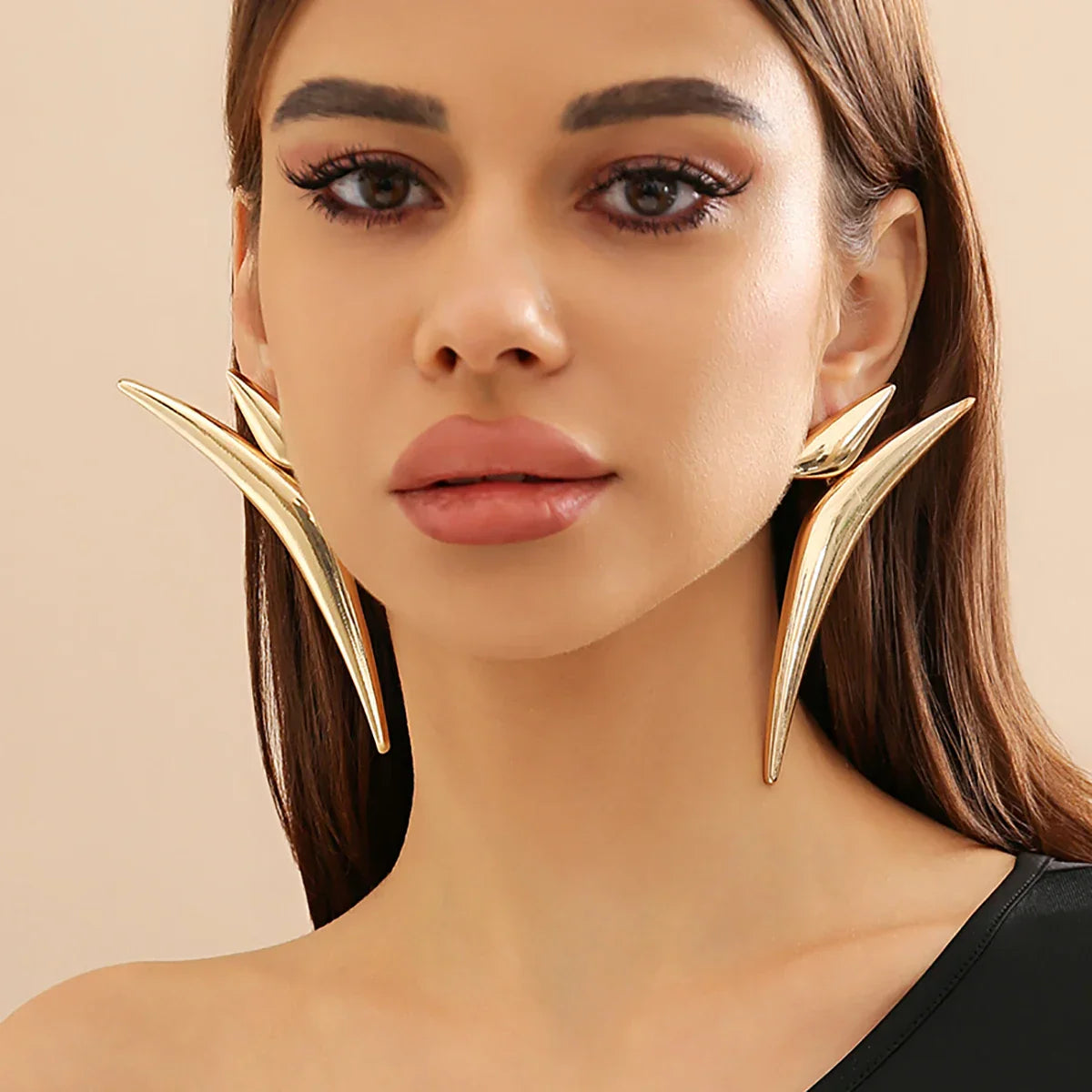 Front-facing view of model wearing Sleek Aeonian Ear Wings. Gold-tone geometric earrings with a sleek and edgy design.