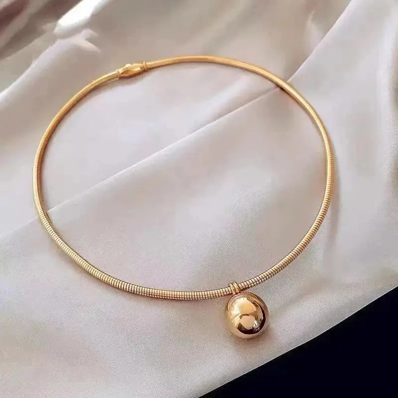 Gold choker necklace featuring a delicate snake chain with a small spherical pendant, ideal for modern jewelry collections.