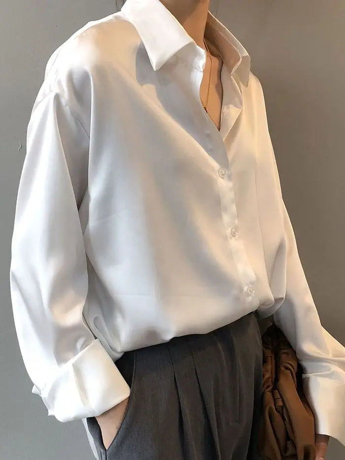 Champagne satin blouse displayed on a hanger, highlighting its silky texture and classic button-down design. A must-have wardrobe staple.