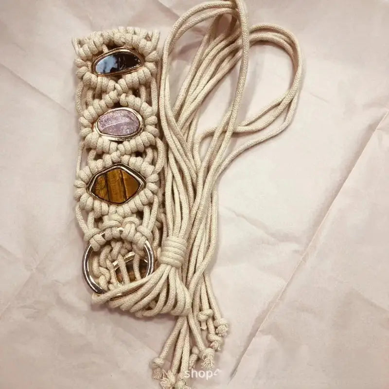 Handmade macramé belt with a braided design, gemstone embellishments, and a metal ring closure. Long tassel ties add a unique bohemian touch.