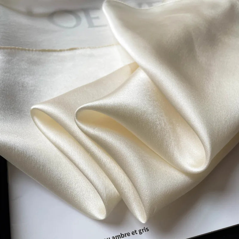 Silk Bandana Scarf - Ivory Elegant features a smooth, glossy texture in pure 100% silk. This timeless ivory hue adds luxury to any outfit.