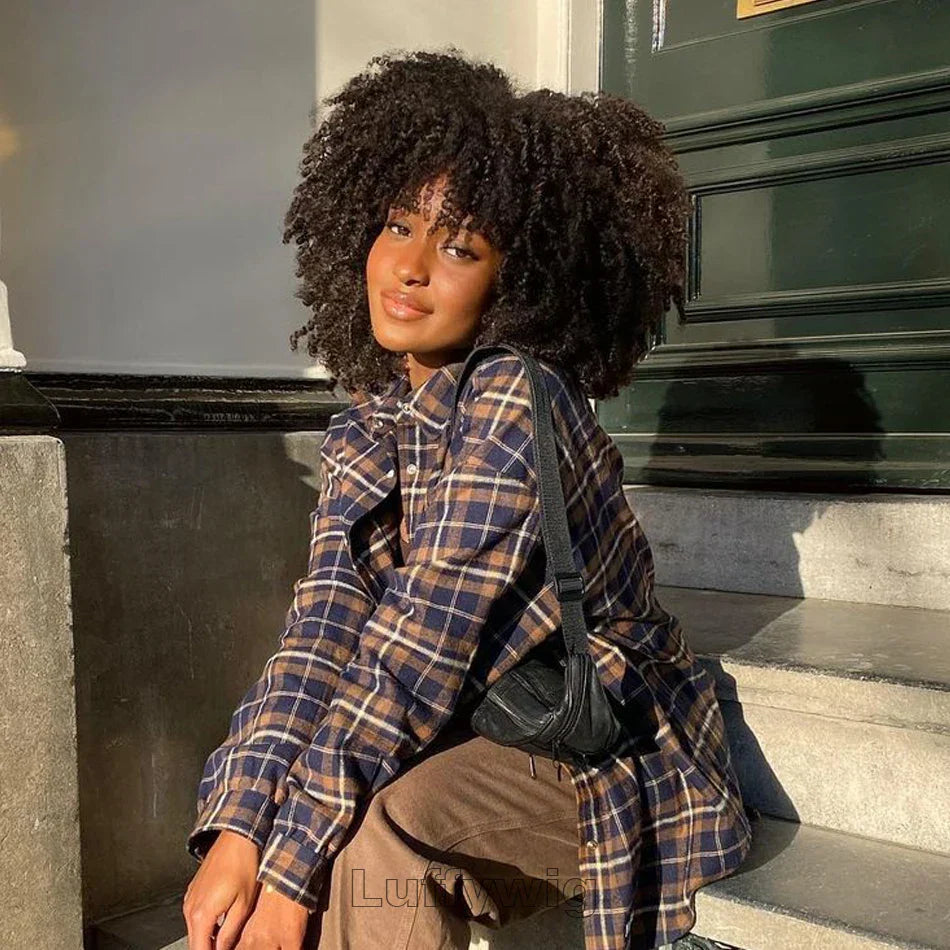Woman wearing a glueless 4B 4C Afro kinky curly Brazilian human hair lace wig, styled naturally with volume and texture, sitting outdoors in sunlight.
