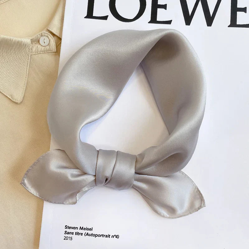 Silk Bandana Scarf - Ivory Elegant tied in a knot, showcasing its smooth 100% silk texture and subtle sheen on a fashion magazine backdrop.